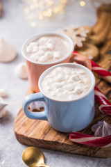 Hot chocolate cacao drinks with marshmallows in Christmas color mugs on grey background. Traditional hot beverage, festive cocktail at X-mas or New Year