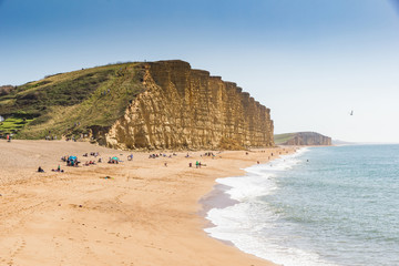 Dramatic layered cliffs of Bridport sandstone along the west Dorset Jurassic coast with Chesil beach disappearing in to the background - obrazy, fototapety, plakaty