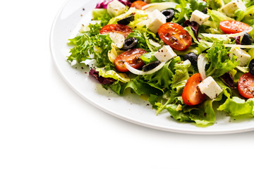 Fresh greek salad on a plate on white background