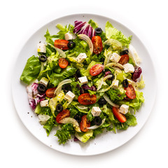 Fresh greek salad on a plate on white background