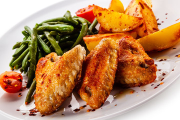 Fried chicken wings with baked potatoes and green beans