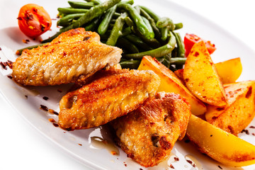 Fried chicken wings with baked potatoes and green beans