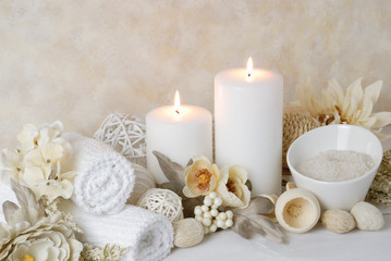 Fototapeta na wymiar spa concept of white burning candles arranged with natural potpourri elements and flowers with bath slats on a warm background