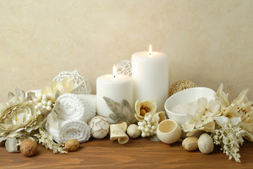 Obraz na płótnie Canvas spa concept of white burning candles arranged with natural potpourri elements and flowers with bath slats on a warm background