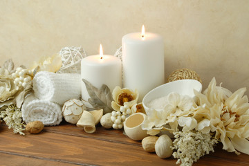 Naklejka na ściany i meble spa concept of white burning candles arranged with natural potpourri elements and flowers with bath slats on a warm background