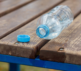 half empty plastic water bottle on a wooden bench