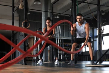Fotobehang Bestsellers Sport Atletisch jong koppel met slag touw doen oefening in functionele training fitness gym.