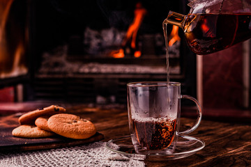 Tea pouring into glass cup on dark background along the Fire