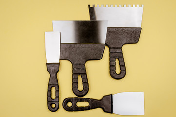 Spatula of different sizes on a yellow background.