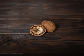a pile of walnuts lie on a wooden table. one of them is chopped