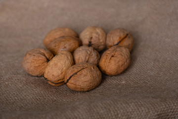 a bunch of whole unpeeled walnuts lie on a linen cloth