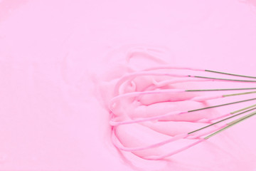 Whipping with a metal whisk of pink cream for baking