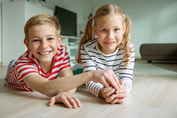 Portrait of two cheerful children laying on the floor and playing with colorful dices