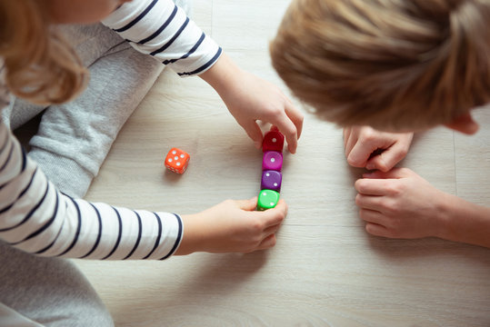 Two clever children study mathematics playing with dices on the floor