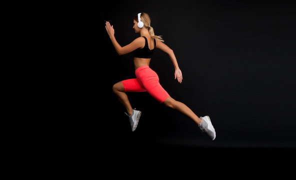 Run hard to get into shape. Woman run black background. Jogger jump with long run. Fit athlete in fashion sportswear. Athletic female sprinter or runner. Active and dynamic. Run fast, finish soon