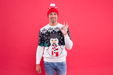 For seasonal comfort. Happy man give OK sign in fashion snowman jumper. Cold weather male style and...