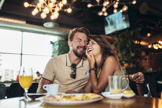 Young happy couple eating pizza in a restaurant