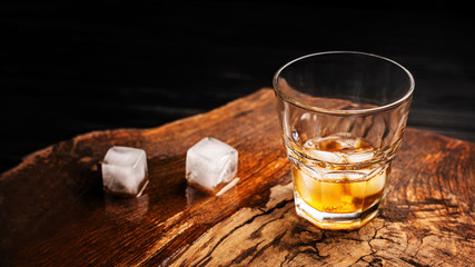 A glass of alcoholic beverage on a wooden table. Whiskey cocktail with ice top view