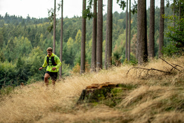 Obraz premium A young athlete in barefoot shoes runs down the mountain. Mountain run. Cross Country Running. Individual sports
