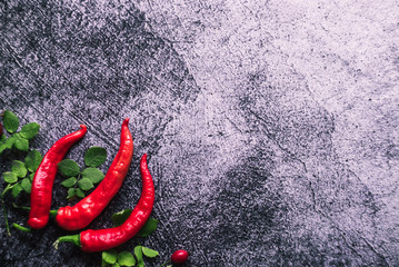 red hot pepper with green leaves lies on a gray concrete background