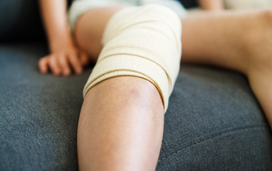 Child knee with gauze bandage. Close-up view.