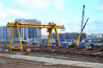 Gantry crane and auto crane working at construction site. Digging a pit for the building of an underground tunnel of the metro line. Subway construction project, Minsk, Belarus, Aerodromnaya street - obrazy, fototapety, plakaty