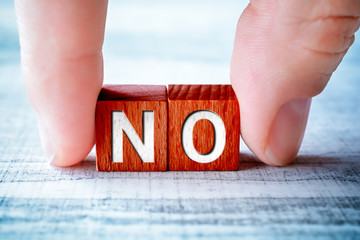 The Word NO On Wooden Blocks And Arranged By Male Fingers On A Table