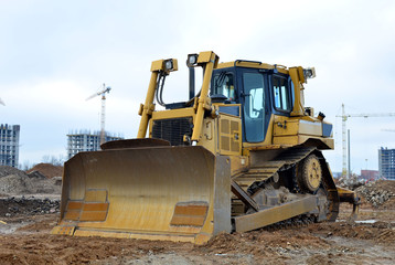 Obraz na płótnie Canvas Bulldozer during of large construction jobs at building site. Land clearing, grading, pool excavation, utility trenching and foundation digging. Crawler tractor, dozer, earth-moving equipment.