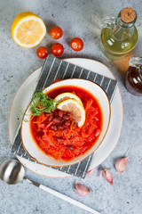 Ukrainian vegetarian borscht with red beans in a white plate stands on a gray concrete background. Top view