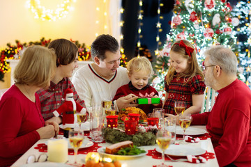Family with kids having Christmas dinner at tree