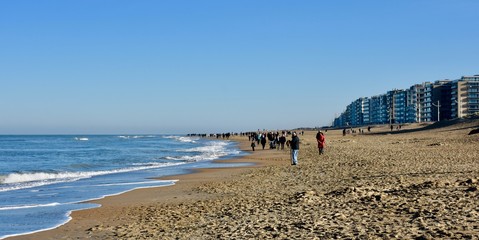  walking people along the Belgian coast on a sunny winter Sunday afternoon between Koksijde and De Panne
