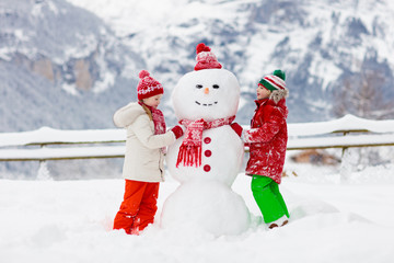 Child building snowman. Kids build snow man.