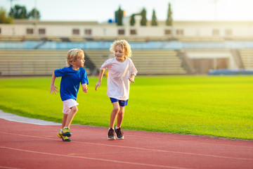 Child running in stadium. Kids run. Healthy sport.