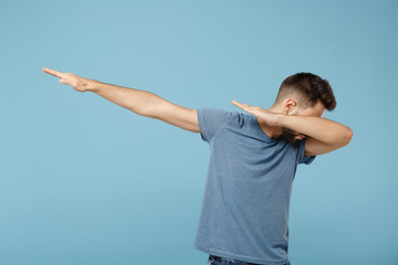 Young man in casual clothes posing isolated on blue wall background, studio portrait. People sincere emotions lifestyle concept. Mock up copy space. Showing dab dance gesture.