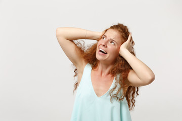 Naklejka premium Young nervous redhead woman in casual light clothes posing isolated on white background in studio. People sincere emotions lifestyle concept. Mock up copy space. Looking up, putting hands on head.