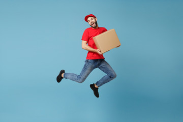 Delivery man in red uniform isolated on blue background, studio portrait. Male employee in cap...