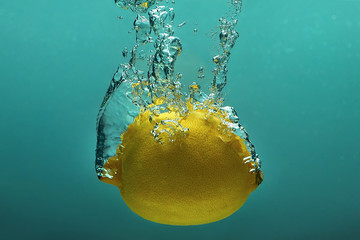 Fruit splash: lemon in the blue water with bubbles - obrazy, fototapety, plakaty