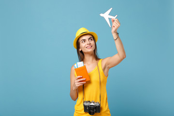 Traveler tourist woman in yellow summer casual clothes hat hold tickets camera isolated on blue background. Female passenger traveling abroad to travel on weekends getaway. Air flight journey concept.