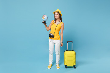 Traveler tourist woman in yellow casual clothes, hat with suitcase photo camera isolated on blue background. Female passenger traveling abroad to travel on weekends getaway. Air flight journey concept