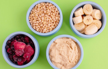 ingredients for making smoothies in bowls - frozen berries, banana, hummus and pine nuts