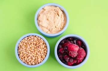 ingredients for making smoothies in bowls - frozen berries, hummus and pine nuts