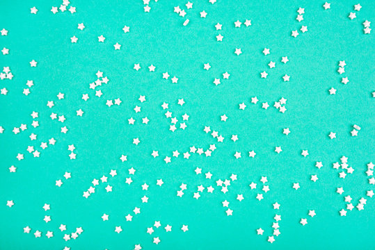 Little white stars on mint background. Holiday concept. Flat lay, top view.