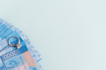 Russian banknotes two thousand rubles and an engagement ring on a blue background with space for text