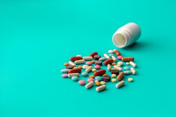 A handful of colored pills spilled out of the can on a blue background. Medical concept