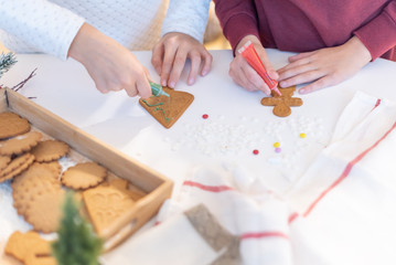 Obraz na płótnie Canvas children decorate ginger Christmas cookies with sugar pencils