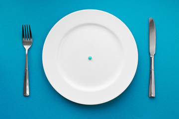 A small tablet in a plate. Medical concept. Eat pills instead of food.