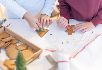 Fototapeta na wymiar children decorate ginger Christmas cookies with sugar pencils