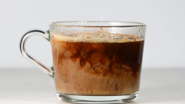 Close Up Pouring Milk In Glass Cup Of Black Coffee