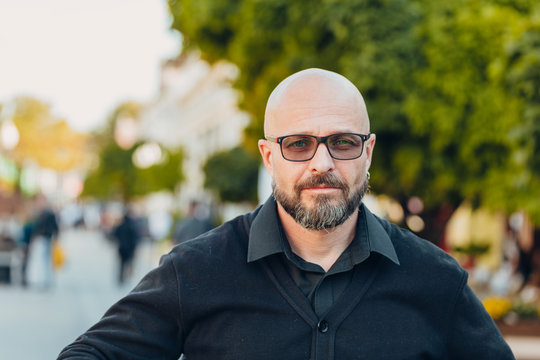 Outdoor Portrait Of A 50 Year Old Happy Man Wearing A Black Shirt And Glasses