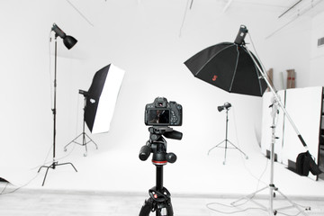 Empty photo studio with lighting equipment and camera - obrazy, fototapety, plakaty